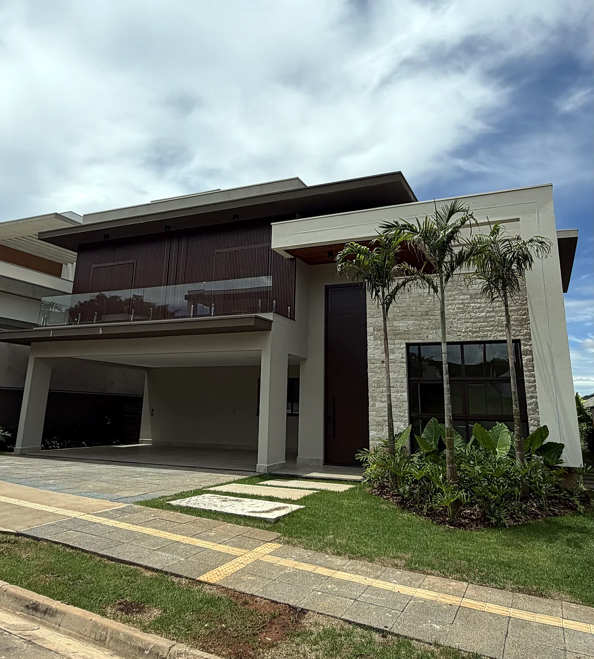 Fachada de casa com palmeiras e revestimento em pedra, obra executada pela HSM Engenharia